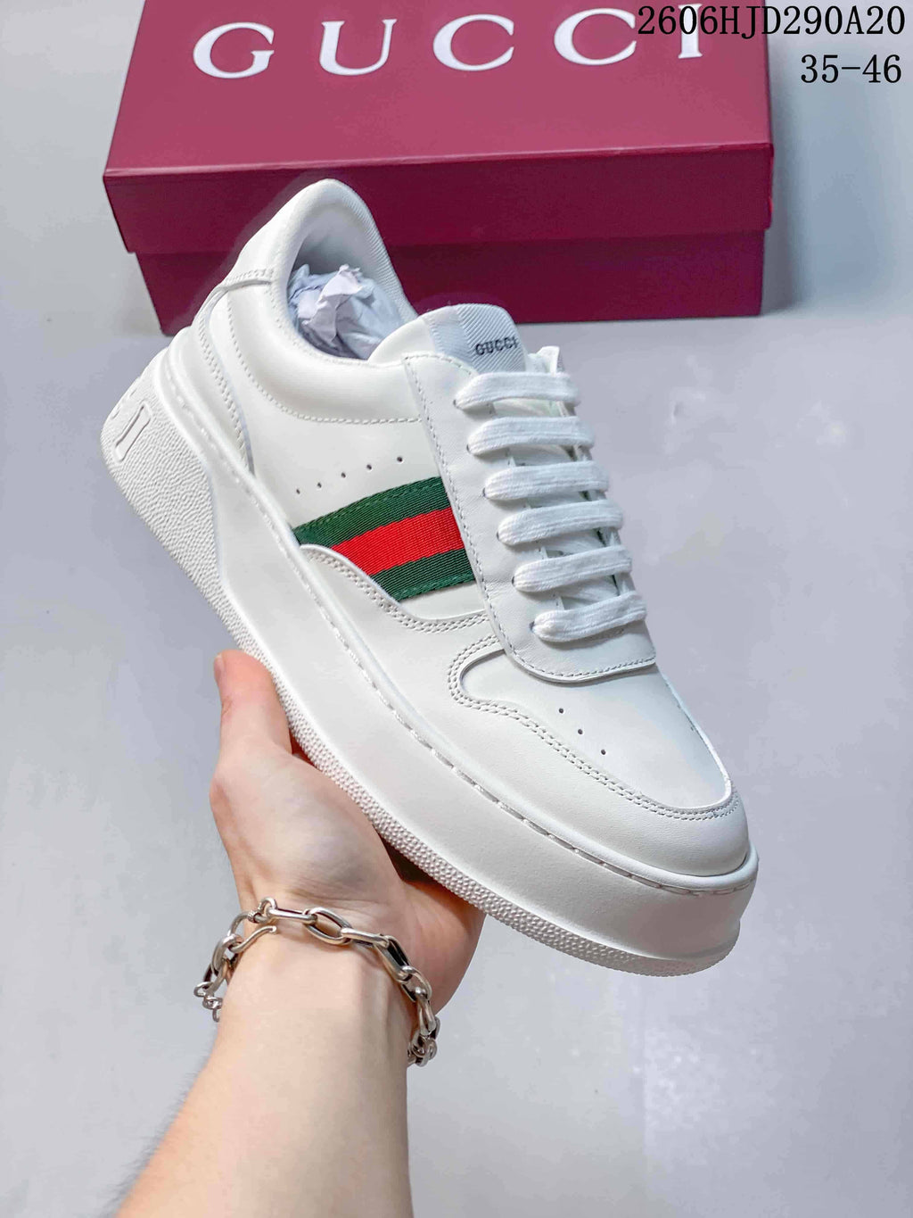 Angled view of the white low-top sneaker with green-and-red side stripe