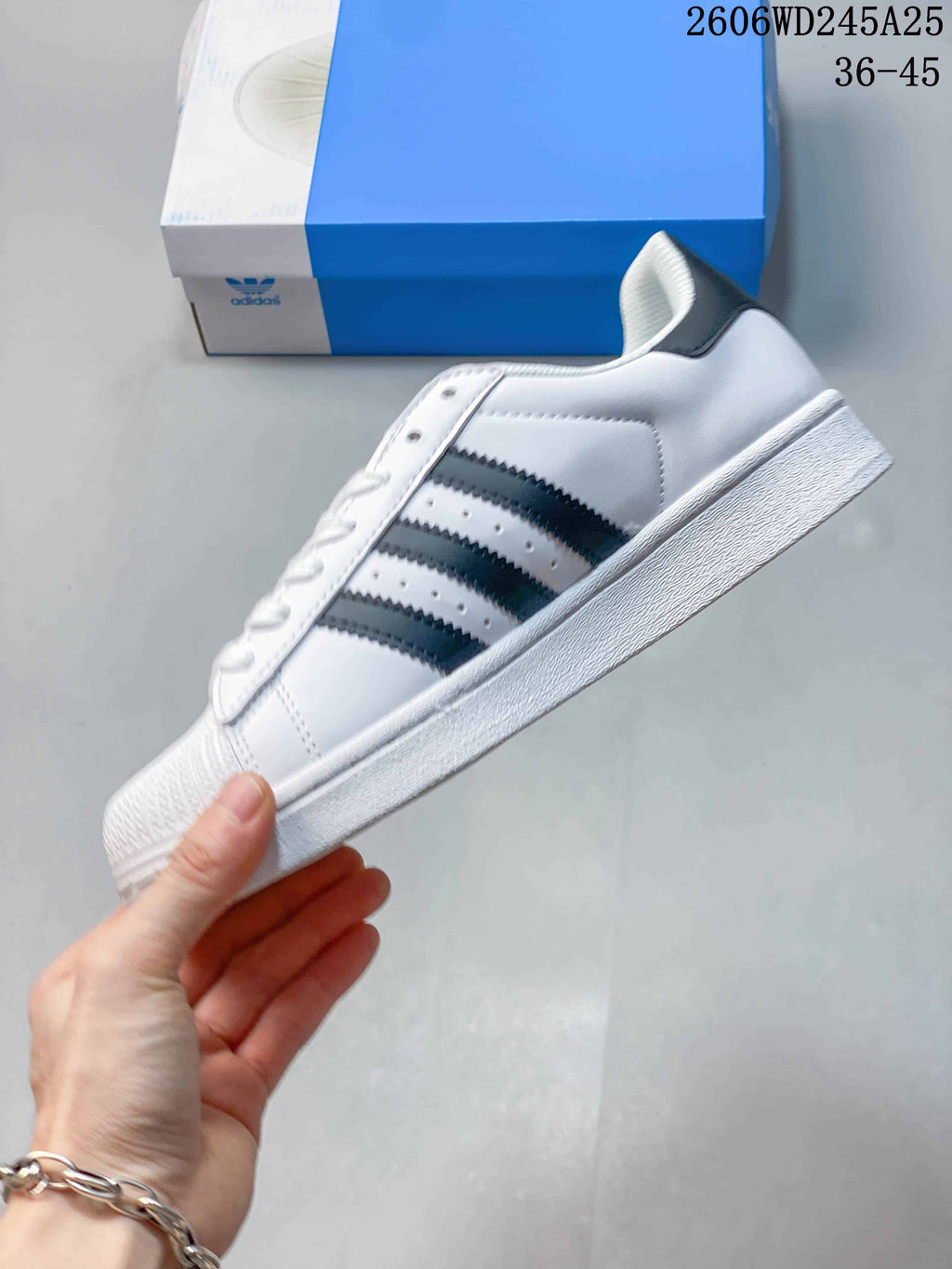 Side profile of the white sneaker with black stripes and a textured shell toe