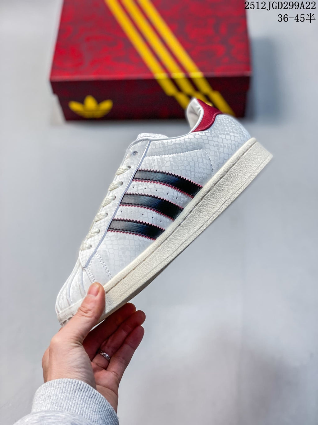 Side profile highlighting the patterned upper, black stripes edged in red, and cream-colored sole.