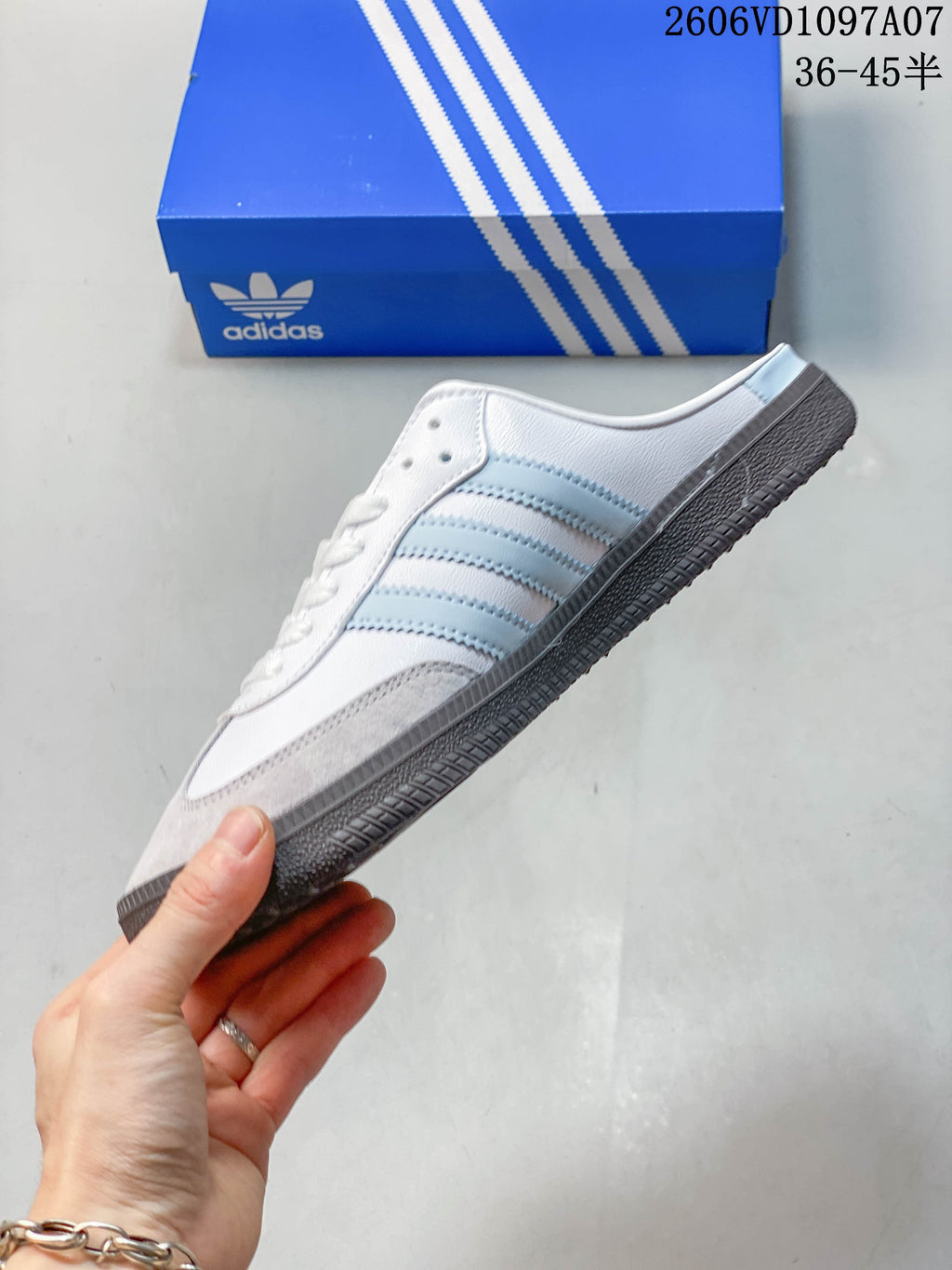 Side profile of a white adidas Samba OG mule with light blue stripes and gray toe overlay