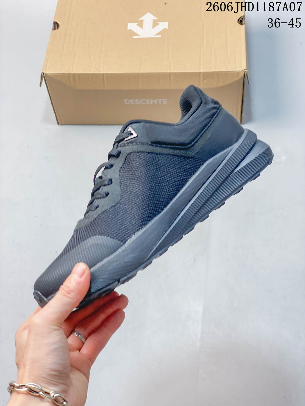 Side profile of a dark charcoal low-top Descente sneaker
