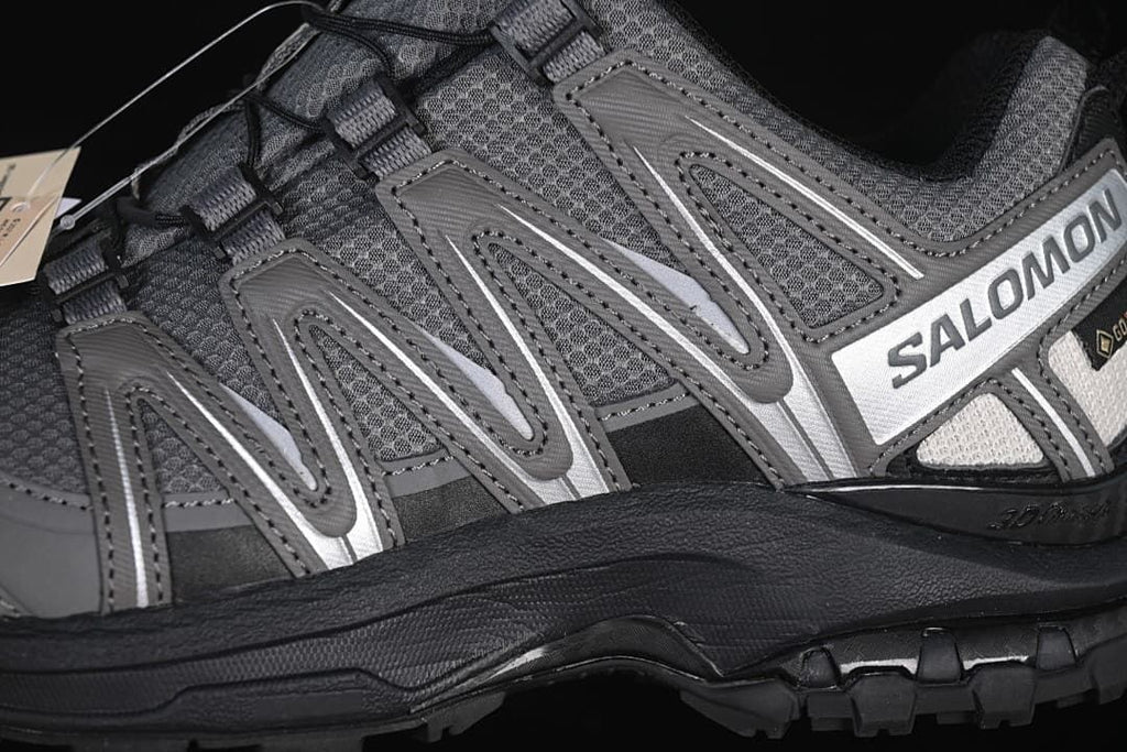 Close-up of the gray side overlays, Salomon branding, and black midsole.