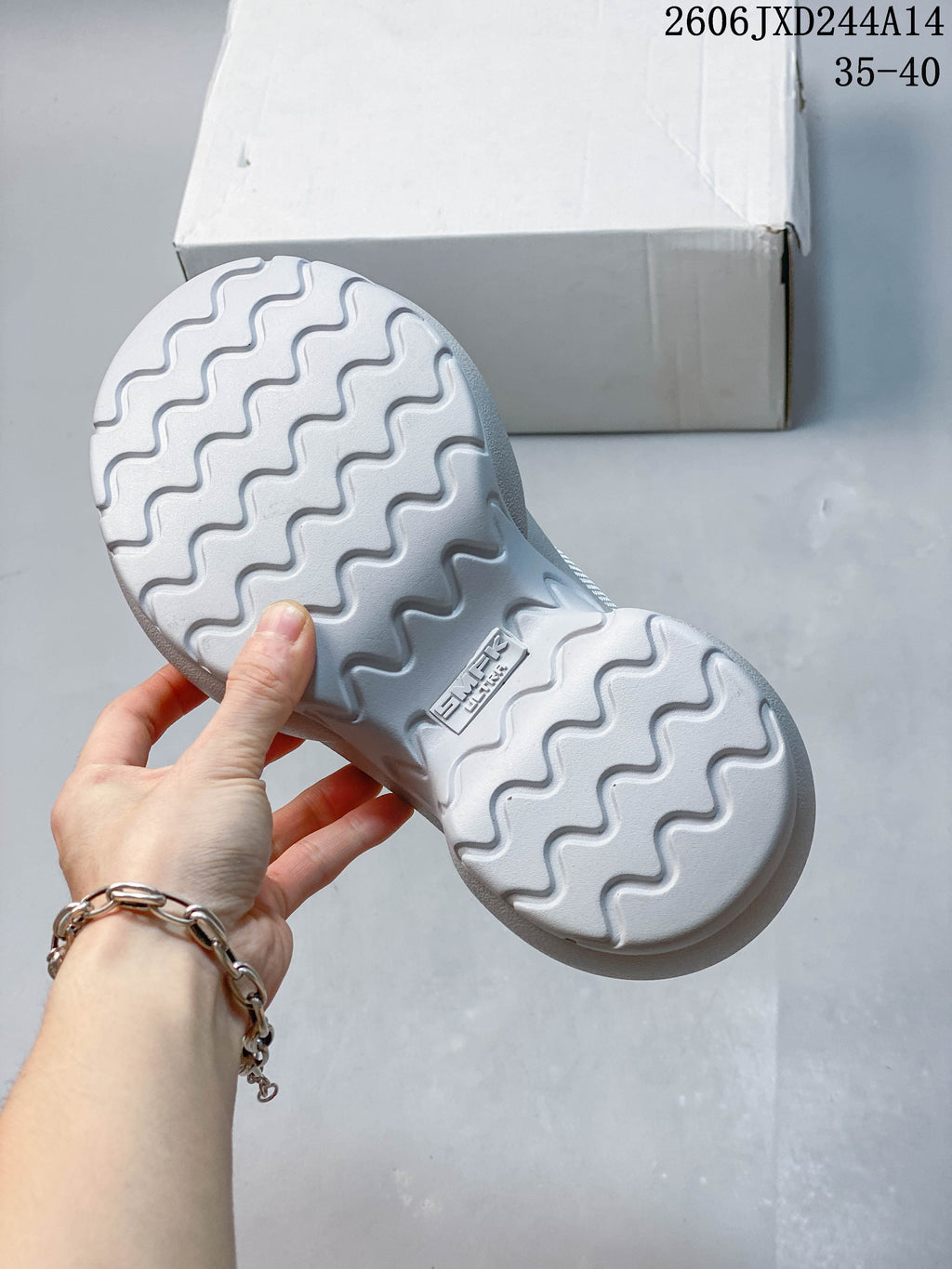 Underside of a pale gray sneaker showing a wavy tread pattern