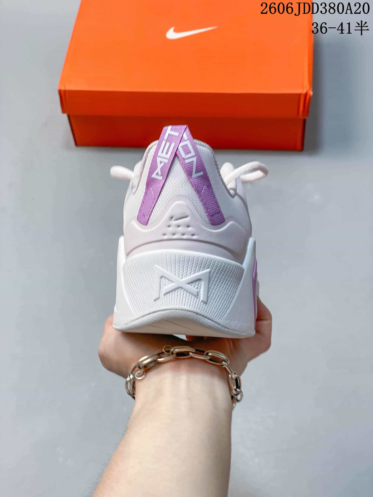 Rear view of the white Nike Free Metcon 7 shoe showing its purple heel pull tabs