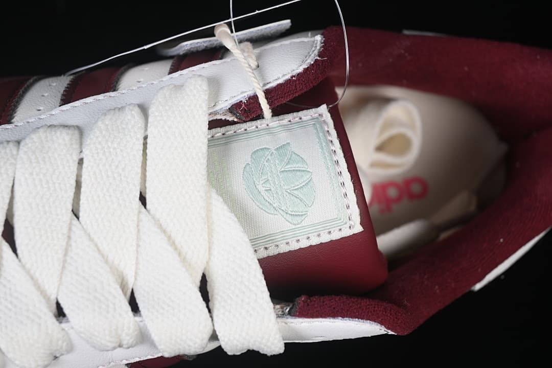 Close-up of white laces, tongue patch, and burgundy lining.
