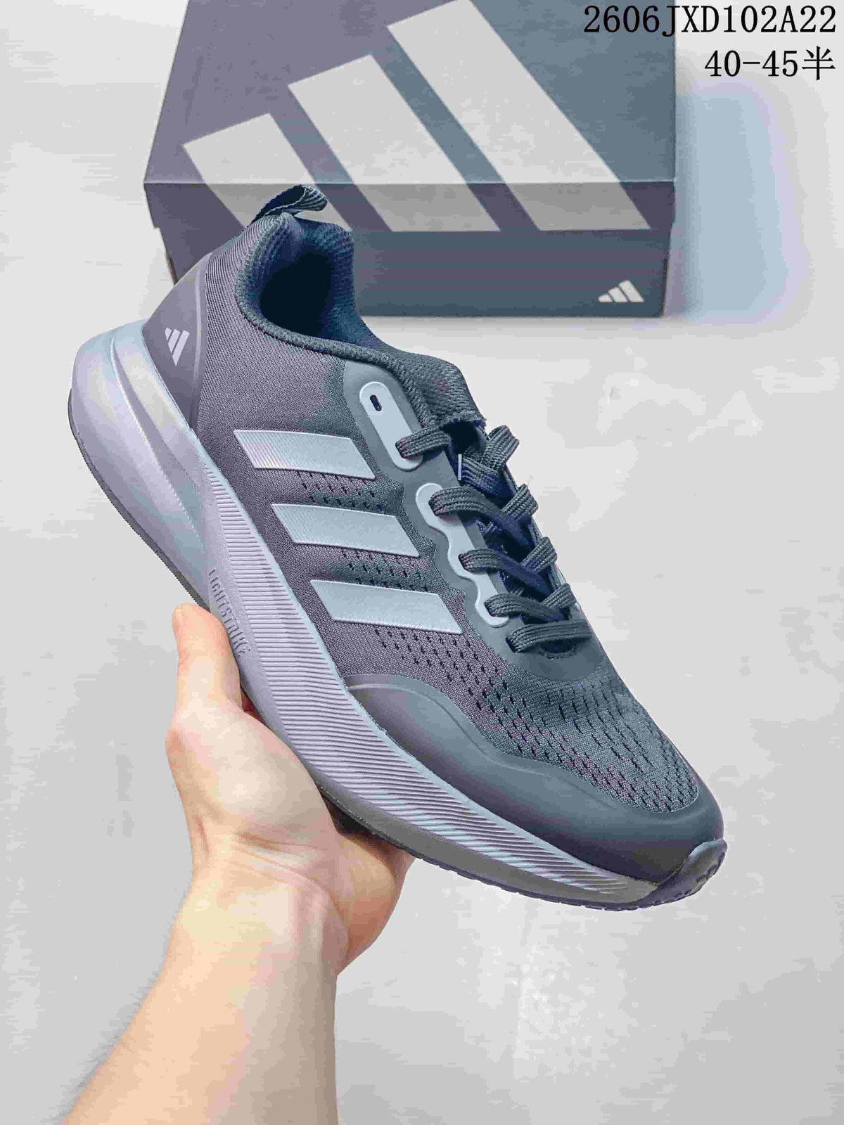 Side view of a dark gray Adidas sneaker with light stripes and a ridged sole.