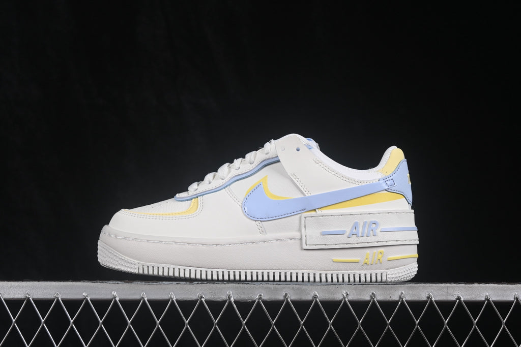 Lateral side view showing the light blue Swoosh, yellow accents, layered heel panels, and raised-looking midsole.