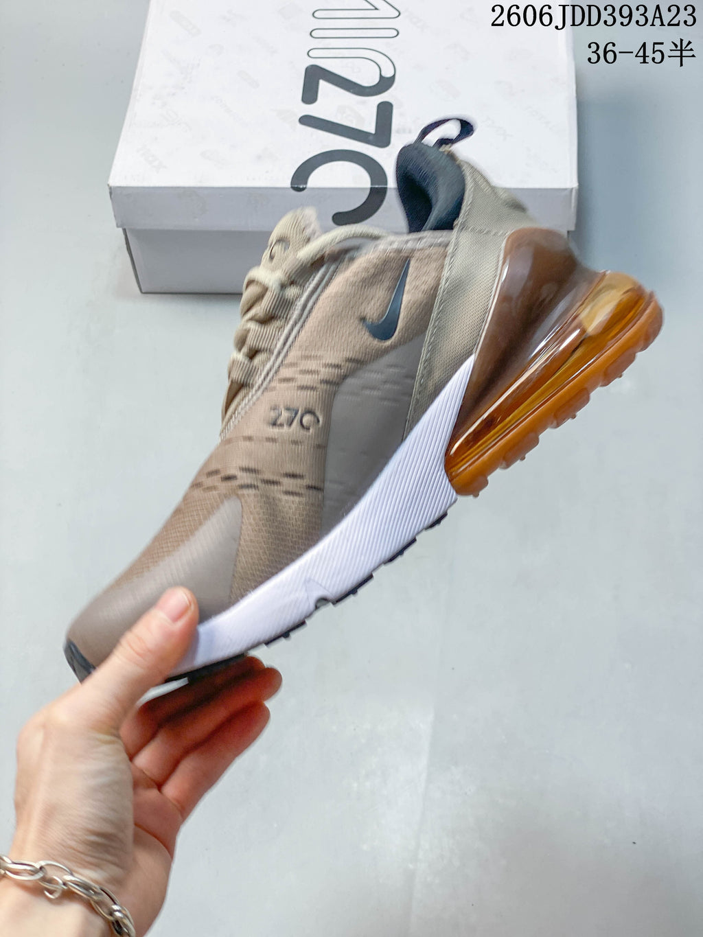 Side view of a beige Nike Air Max 270 sneaker with a white midsole and amber-colored heel unit.