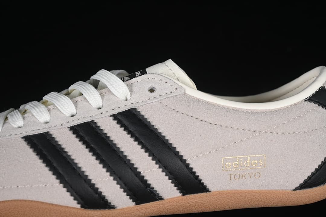 Close-up of the cream upper, black stripes, laces, and Tokyo branding