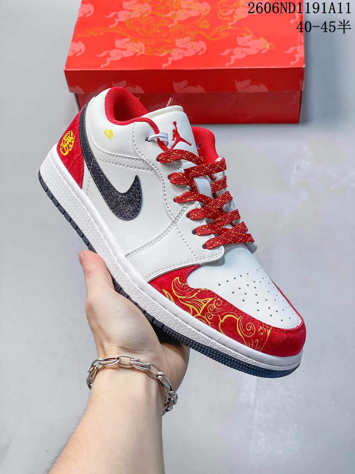 Angled view of the white and red low-top sneaker with a dark Swoosh and gold-toned decorative detailing.