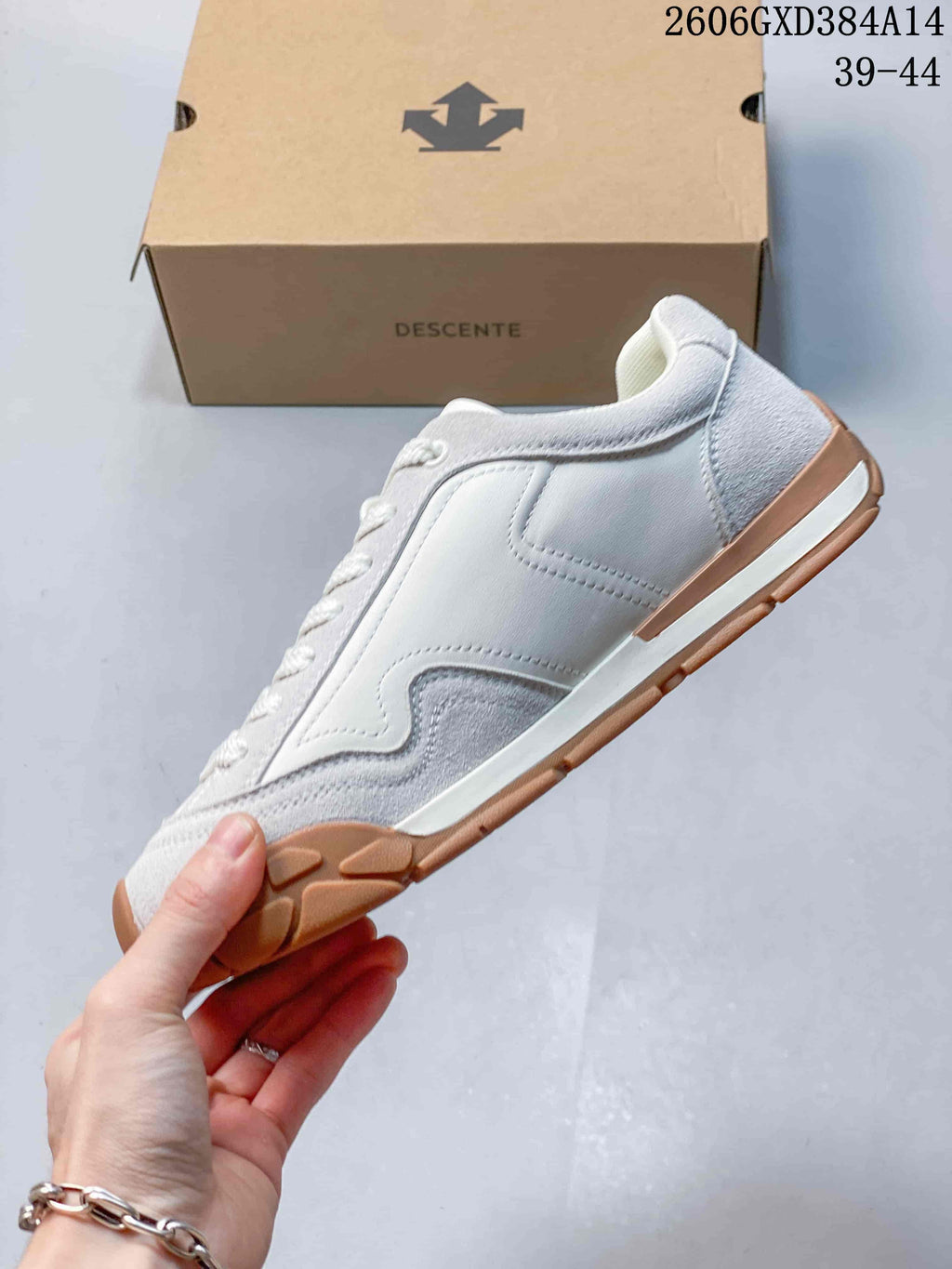 Side view of a white and light gray lace-up sneaker with a gum-colored sole.