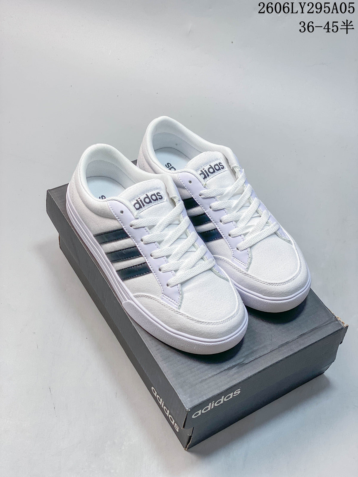 Pair of white adidas low-top sneakers with dark three-stripe side details.