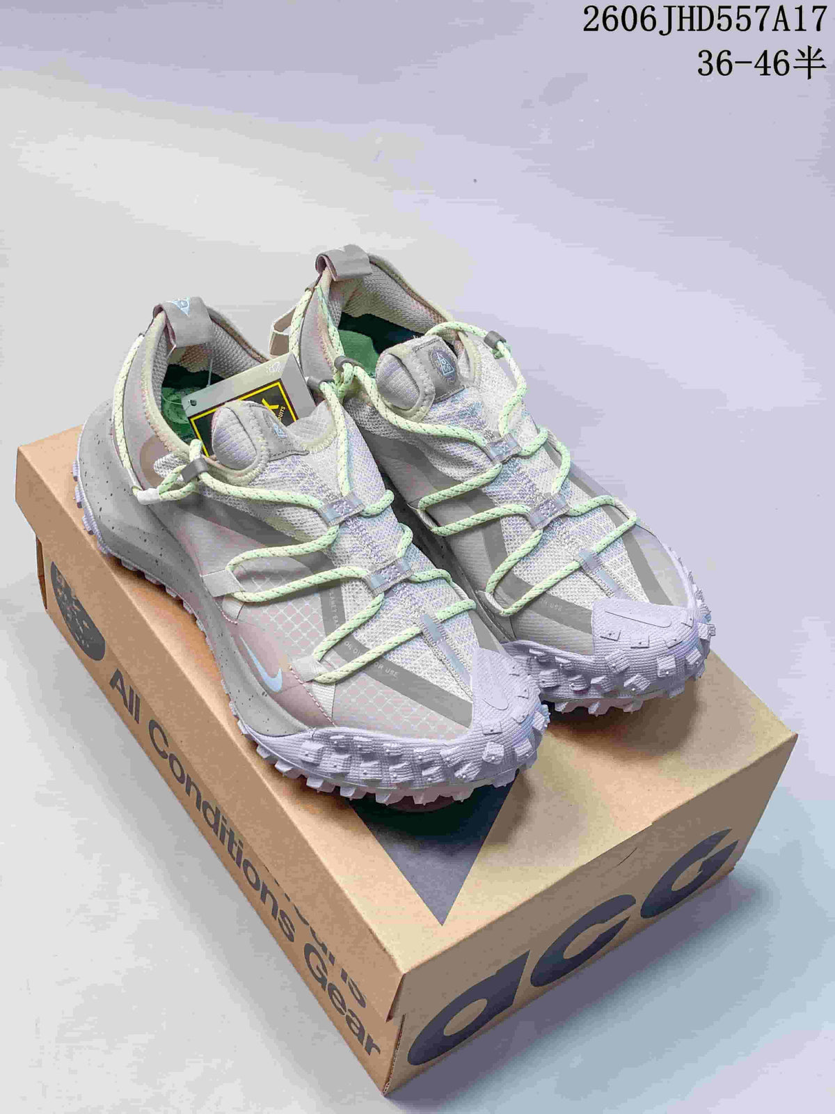 Pair of pale gray and lavender Nike ACG Mountain Fly sneakers with mint-green laces, shown on an ACG box.
