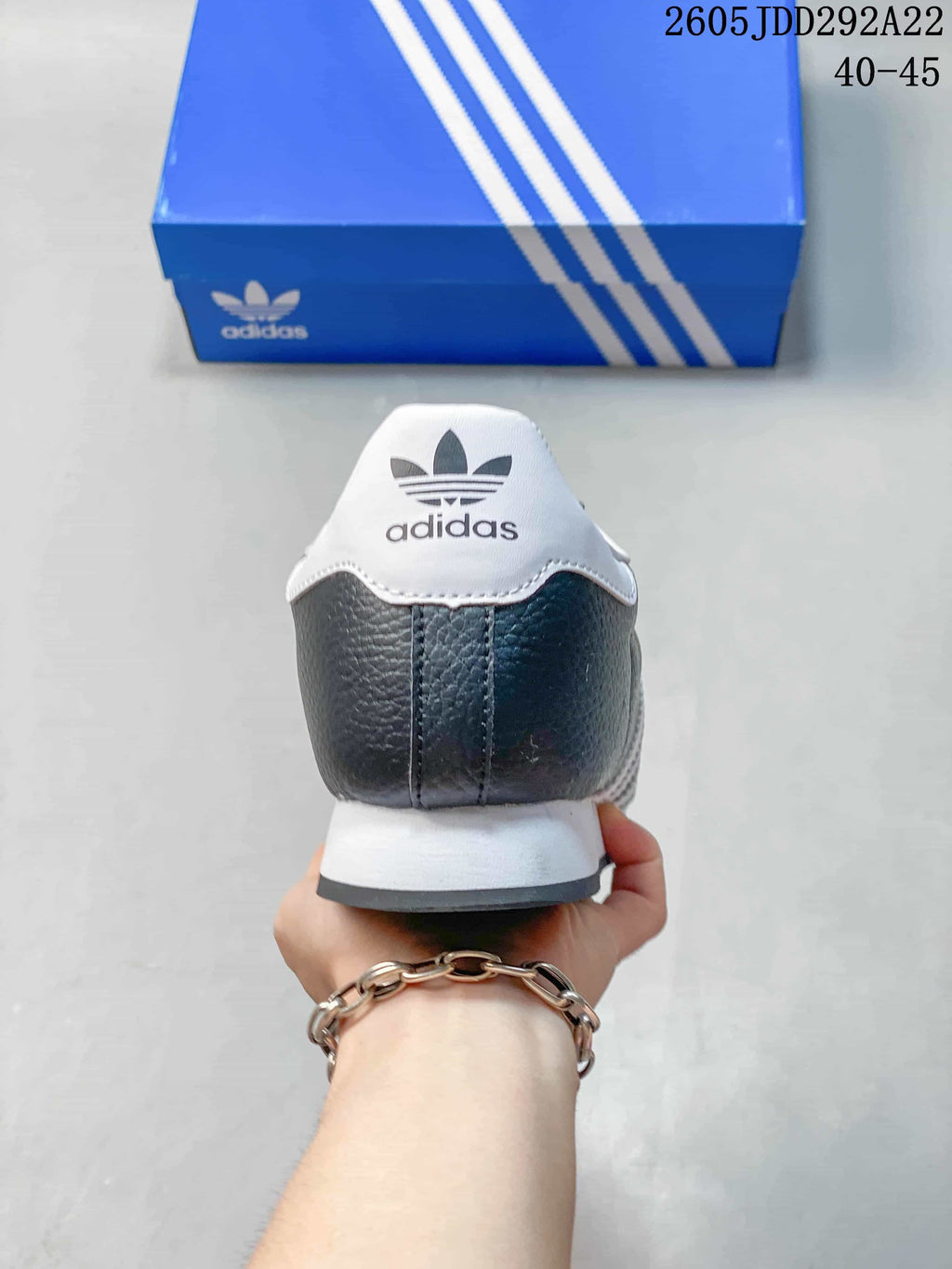 Rear view of a charcoal Adidas Samoa sneaker with a white heel panel