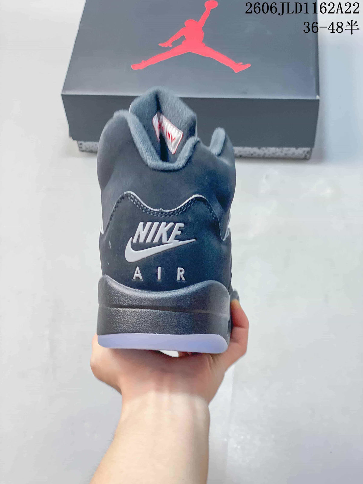 Rear view of a dark high-top sneaker showing the heel branding and translucent outsole edge.
