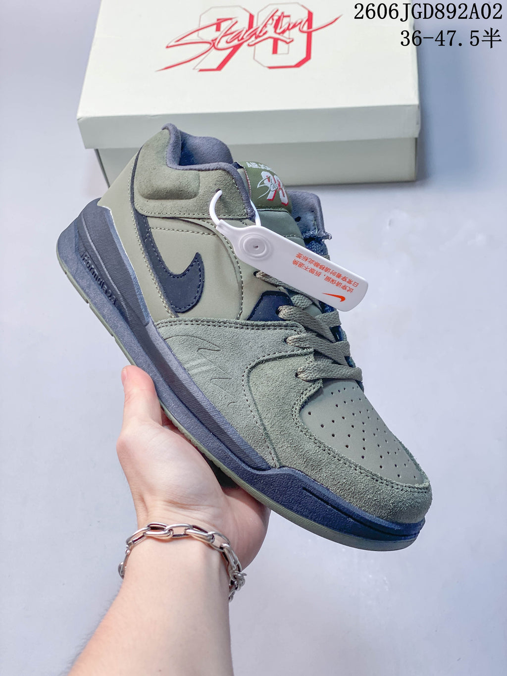 Angled side view of a sage-green and navy Jordan Stadium 90 sneaker.