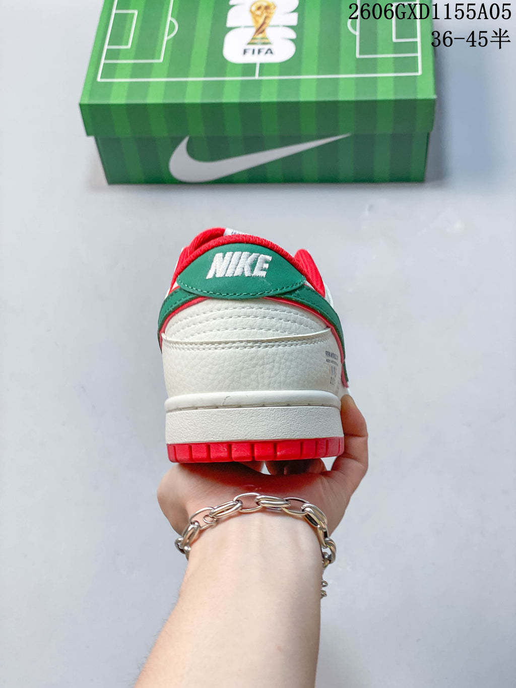 Rear view showing the sneakers’ red outsole, green heel accent, and off-white upper