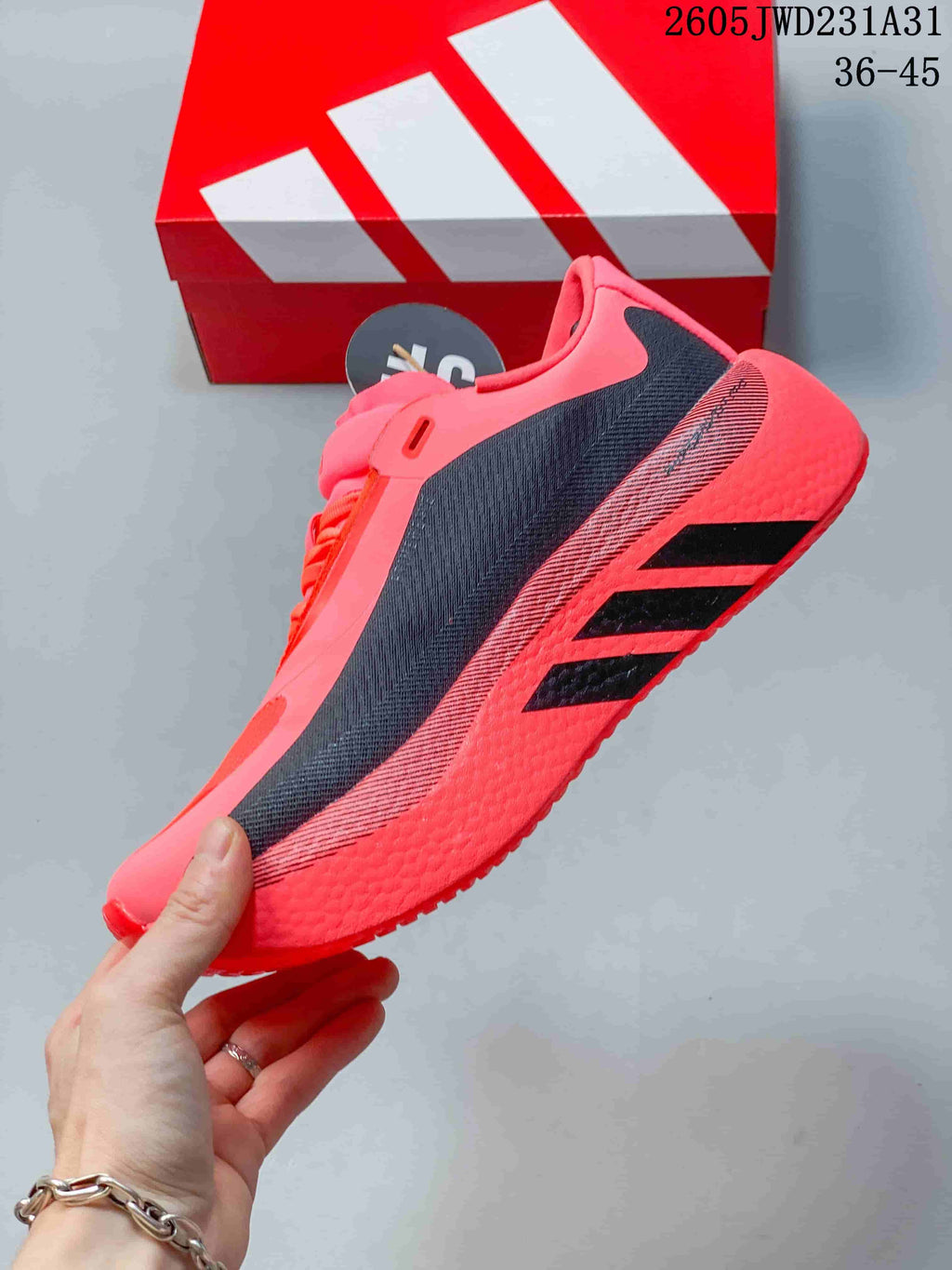 Side view of the bright pink shoe showing dark side panels and three black stripes.