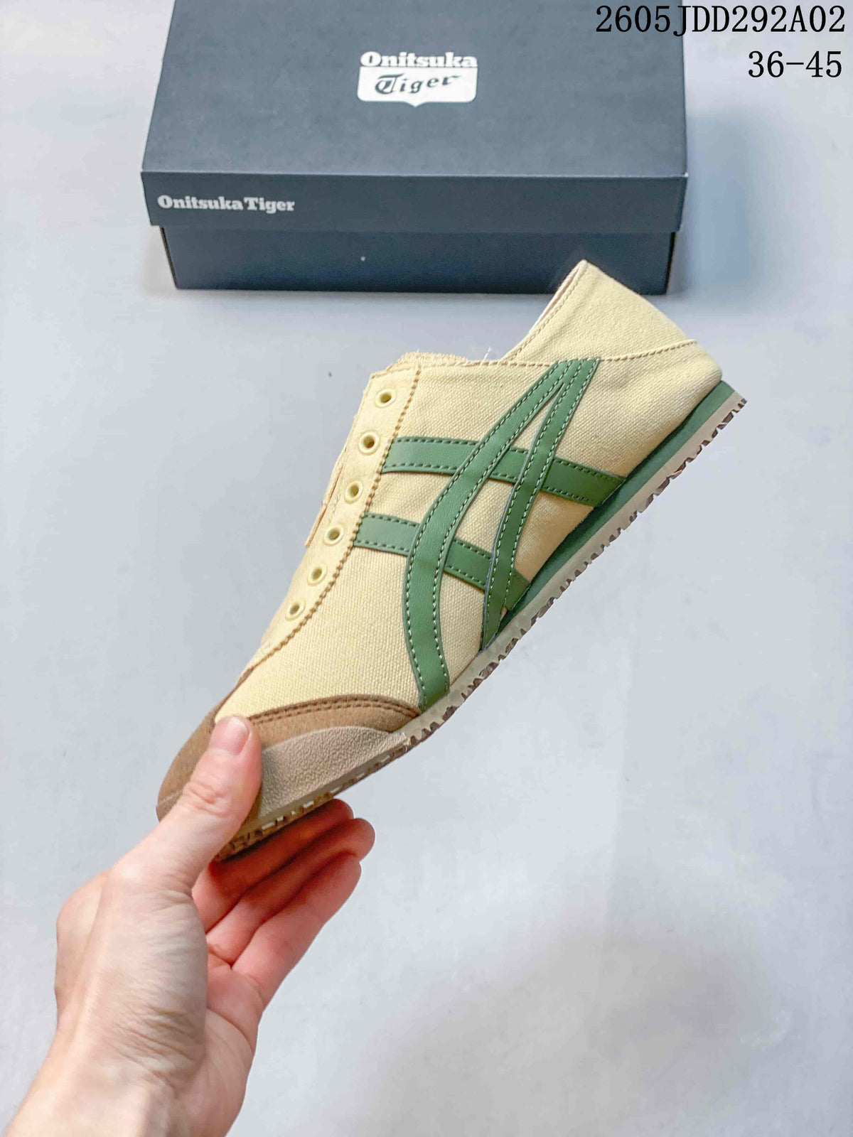 Side view of the beige slip-on sneaker showing green stripes, a brown-toned toe overlay, and textured outsole.