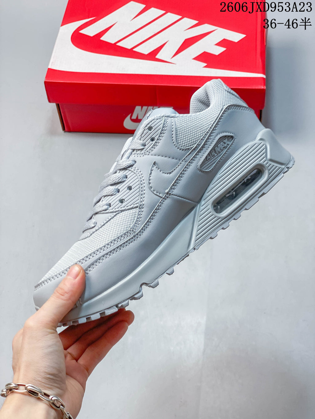 Side view of a light grey Nike Air Max 90 sneaker with a visible heel air unit