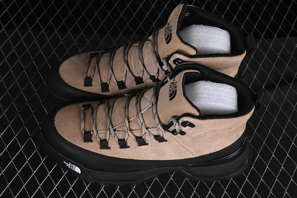 Pair of brownish-black mid-cut boots with black trim and chunky soles