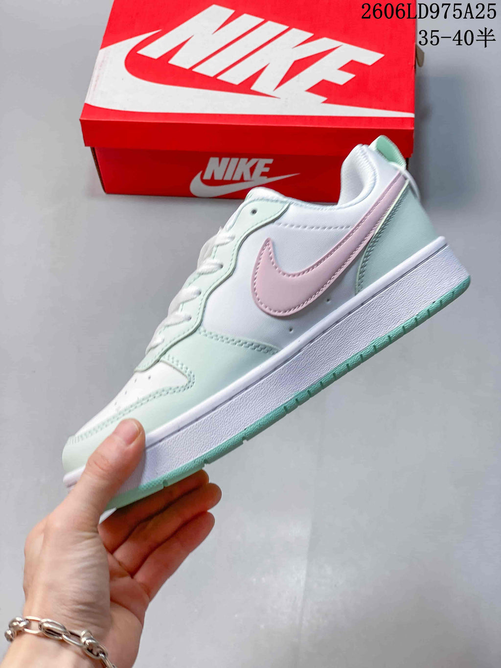 Side view of a white Nike Court Borough Low sneaker with pink Swoosh and mint overlays.