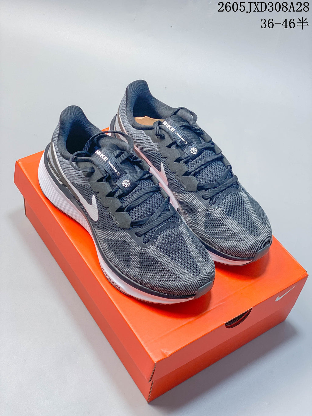 Pair of charcoal gray Nike Air Zoom Structure 25 running shoes with white accents, shown on an orange shoe box.