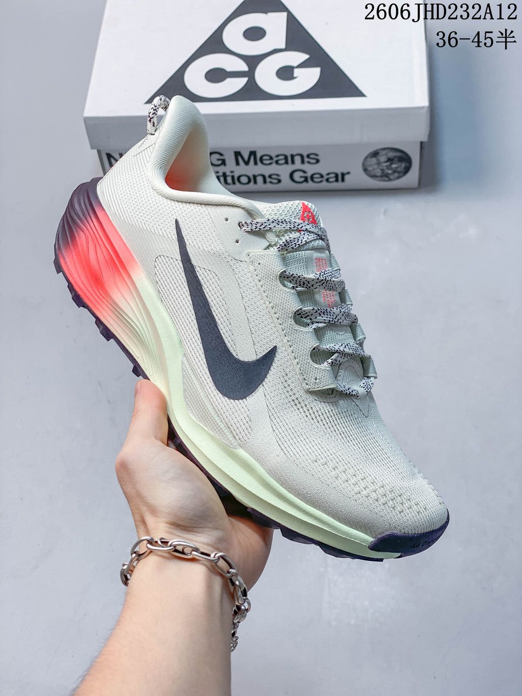 Angled side view of the Nike ACG Pegasus Trail shoe with pale upper, dark swoosh, and coral heel accent.