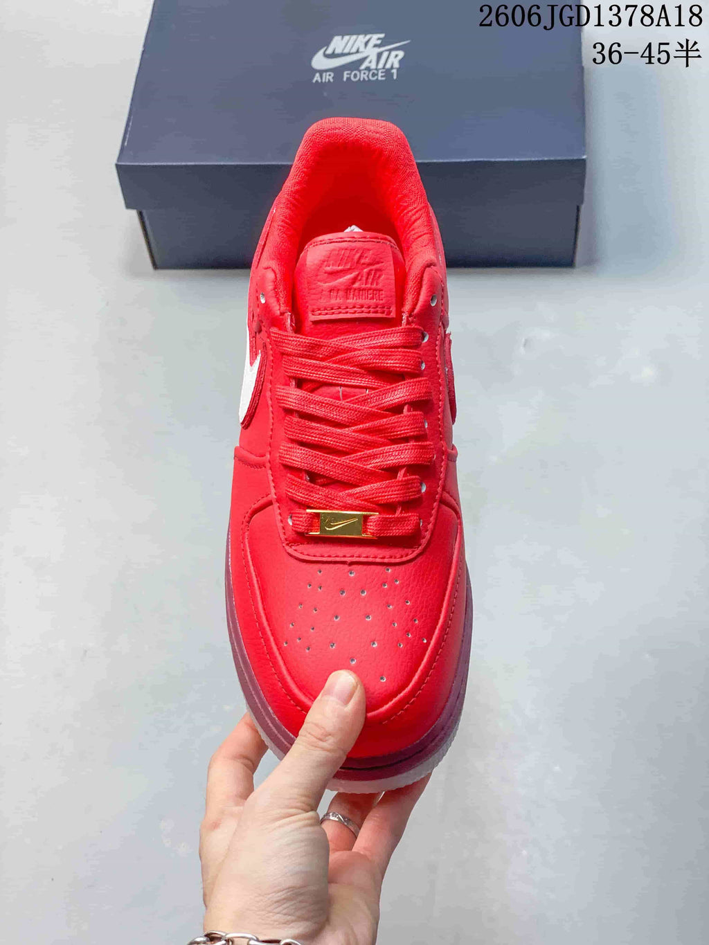 Top view of a red low-top sneaker showing laces, perforated toe, and gold-tone lace tag