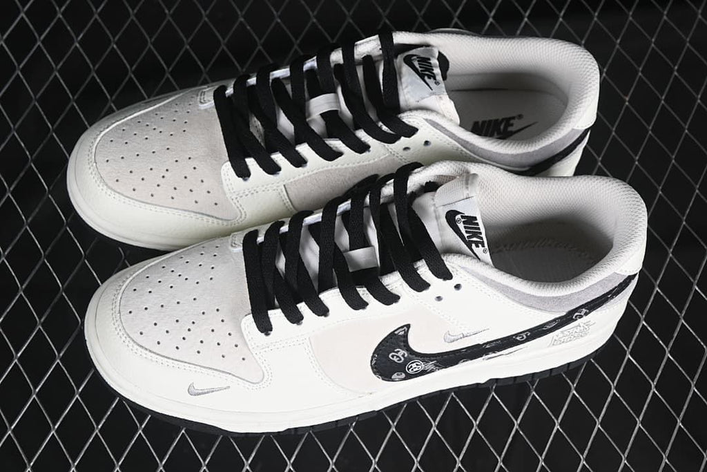 Pair of white and gray low-top sneakers with black laces and patterned side Swooshes