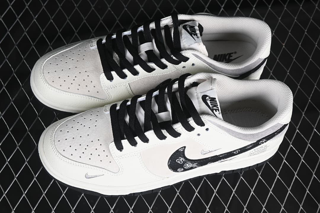Pair of white and gray low-top sneakers with black laces and patterned side Swooshes