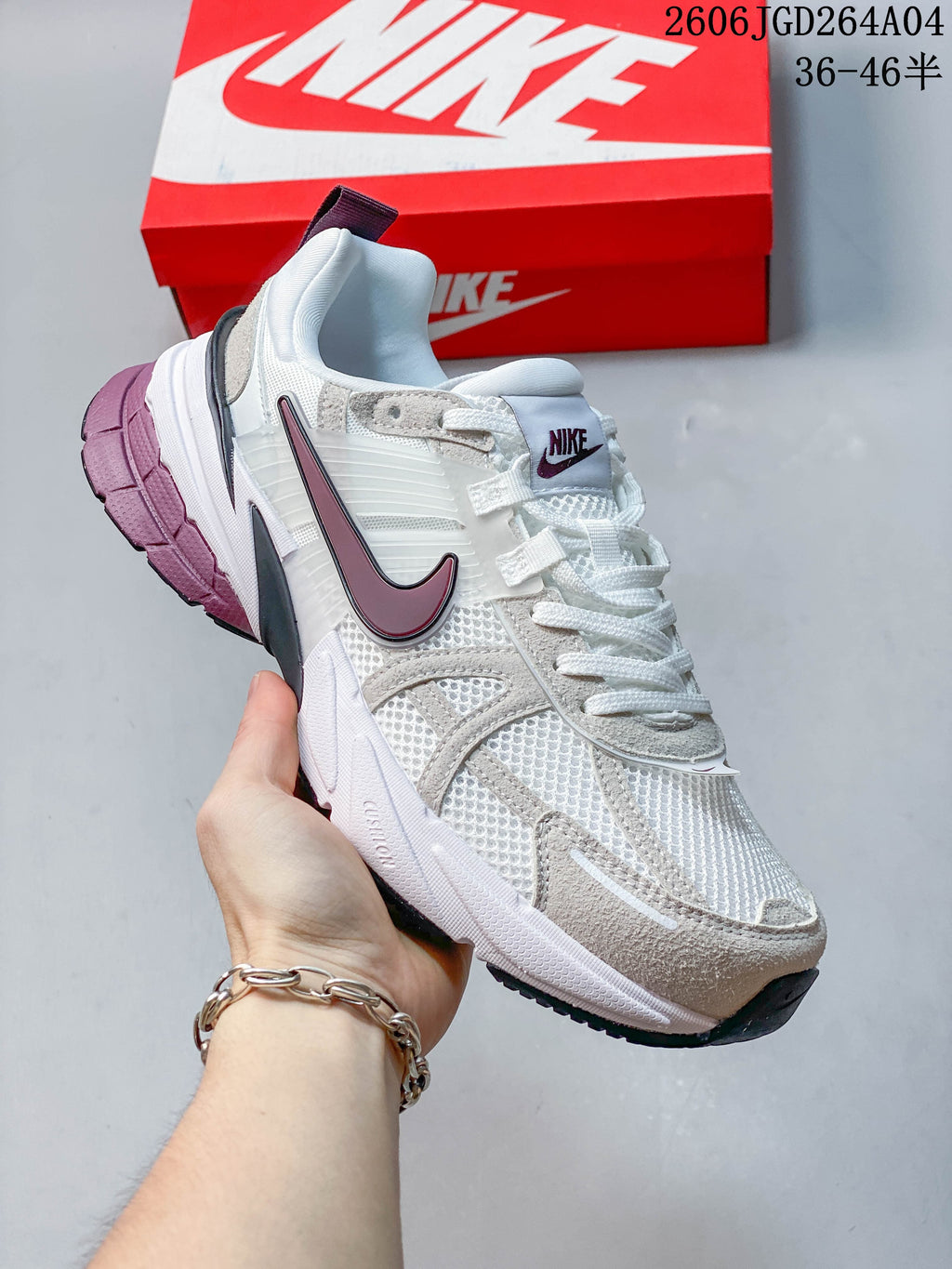 Angled side view of a white Nike V2K Run sneaker with plum accents