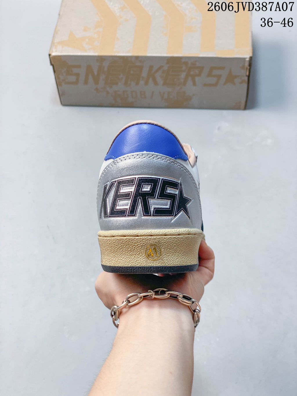 Rear view of the sneaker with a blue heel accent and branded silver heel panel
