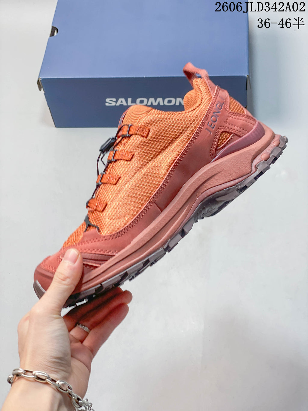 Side view of the coral trail shoe with cord lacing and layered overlays.