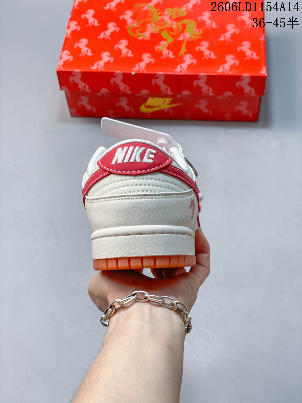 Rear view of an off-white low-top sneaker with a red heel tab and orange outsole.