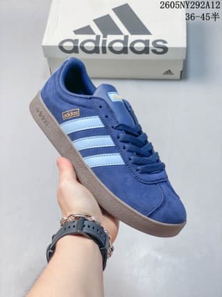Angled view of the blue Adidas sneaker with white stripes and a gum-style sole.