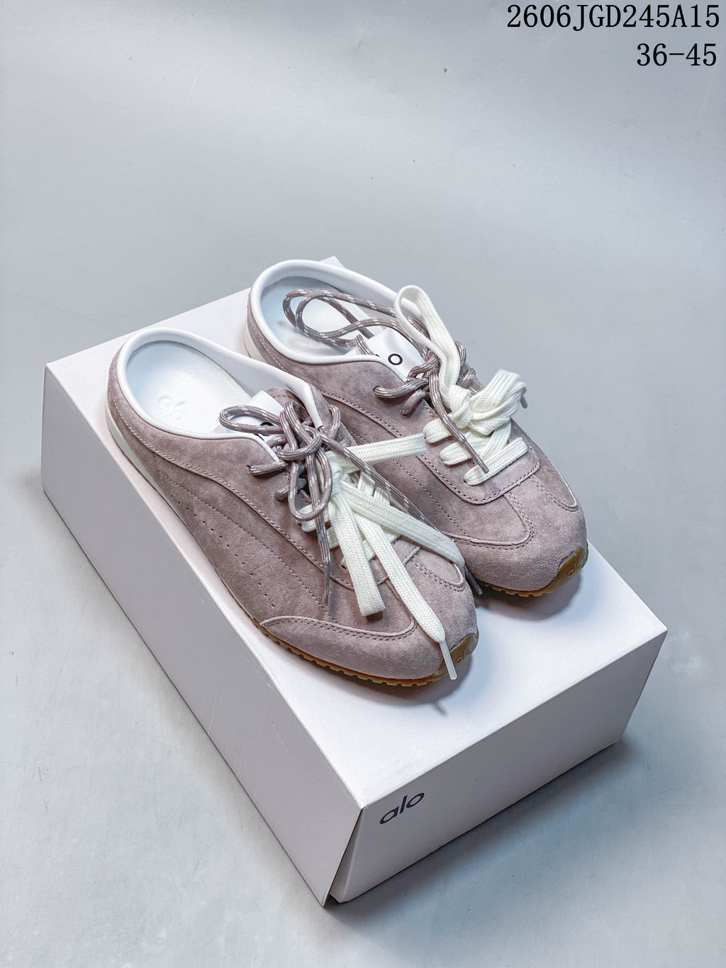Pair of mauve-taupe Alo Yoga lace-up sneakers with contrasting laces on a box