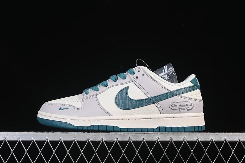 Side view of white and light gray Nike SB Dunk Low shoes with teal accents and patterned side swoosh