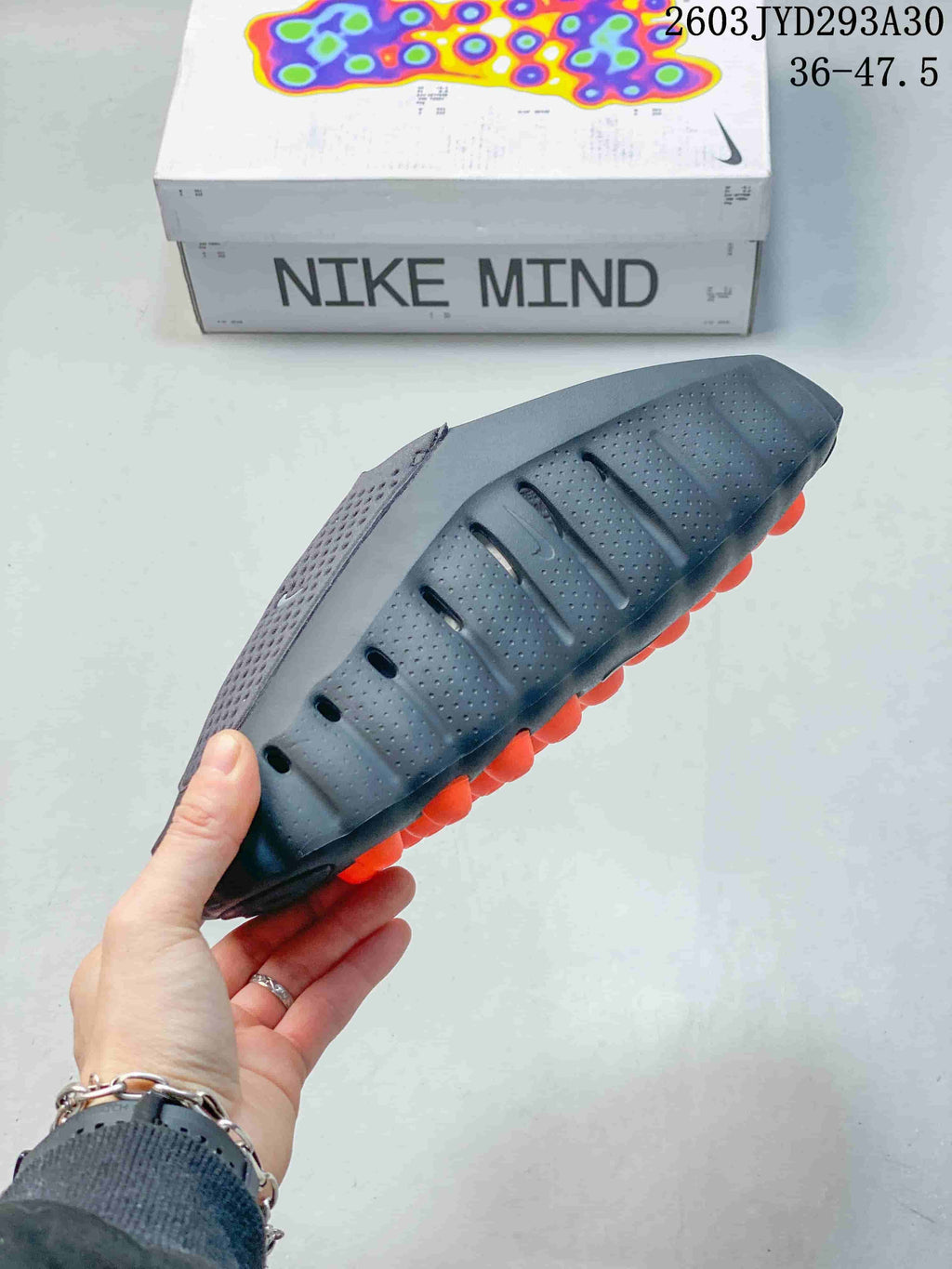 Side view of a Nike Mind slide showing its textured upper and orange outsole pods