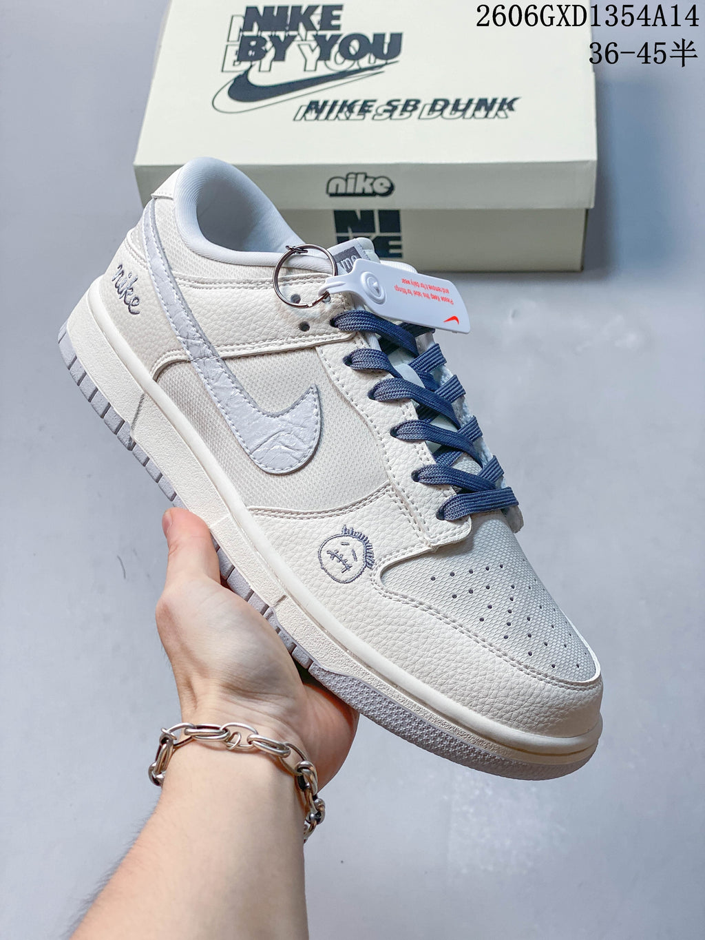 Side view of an off-white Nike Dunk Low sneaker with navy laces and embroidered details
