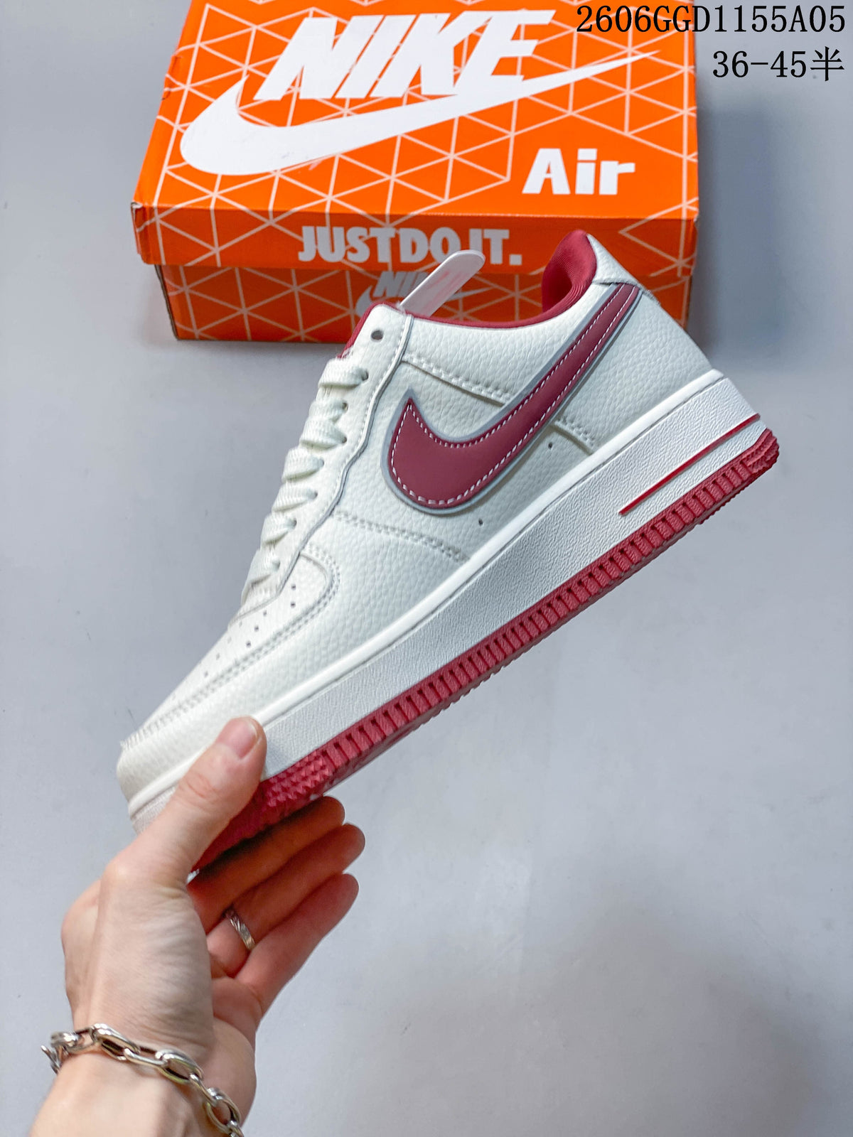 Side profile of the white low-top sneaker with a burgundy-red Swoosh and outsole