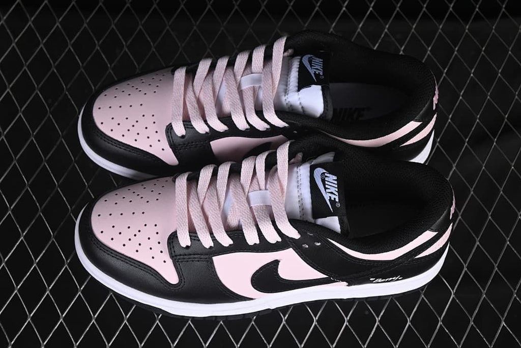 Top view of a pair of black and pale pink low-top sneakers showing perforated toes and pale laces.