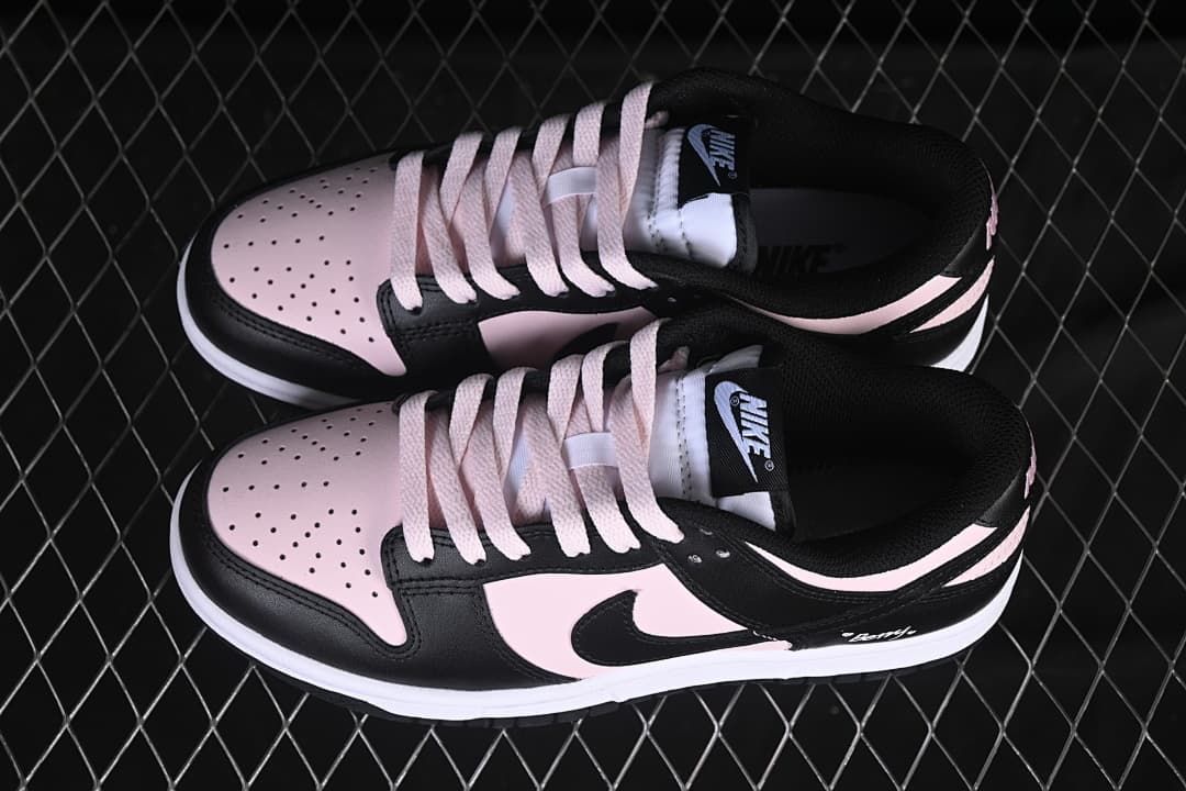 Top view of a pair of black and pale pink low-top sneakers showing perforated toes and pale laces.