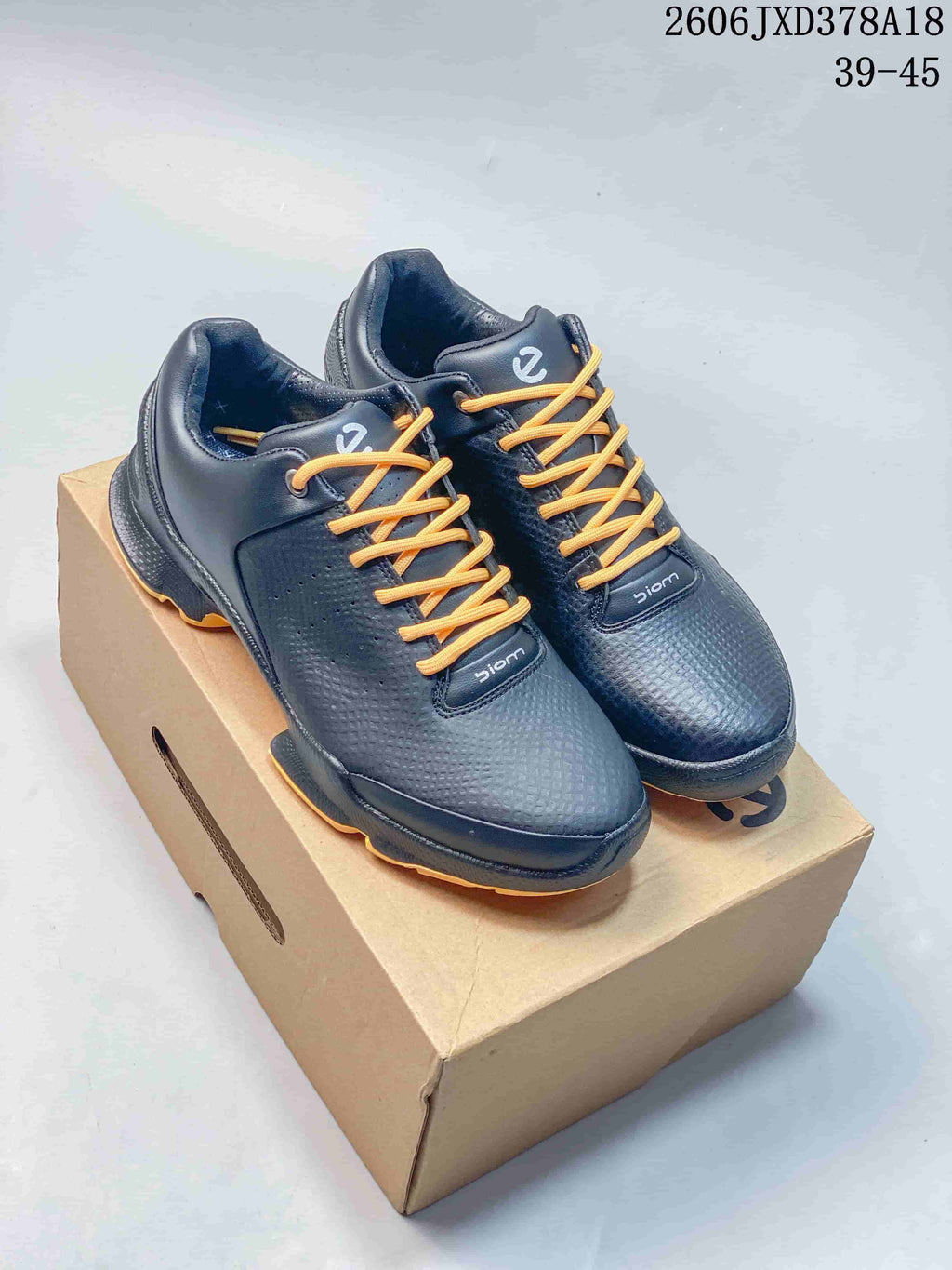 Pair of black ECCO BIOM sneakers with orange laces and orange outsole accents.
