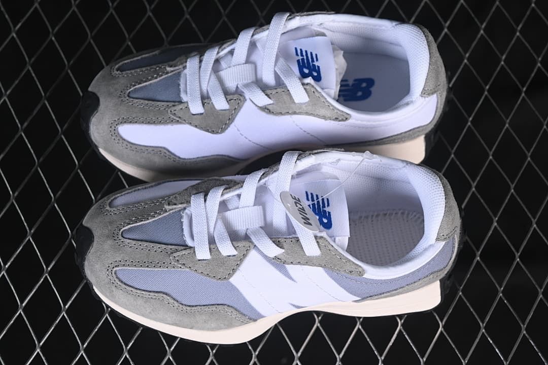 Overhead view of a pair of grey and white New Balance 327 kids sneakers.