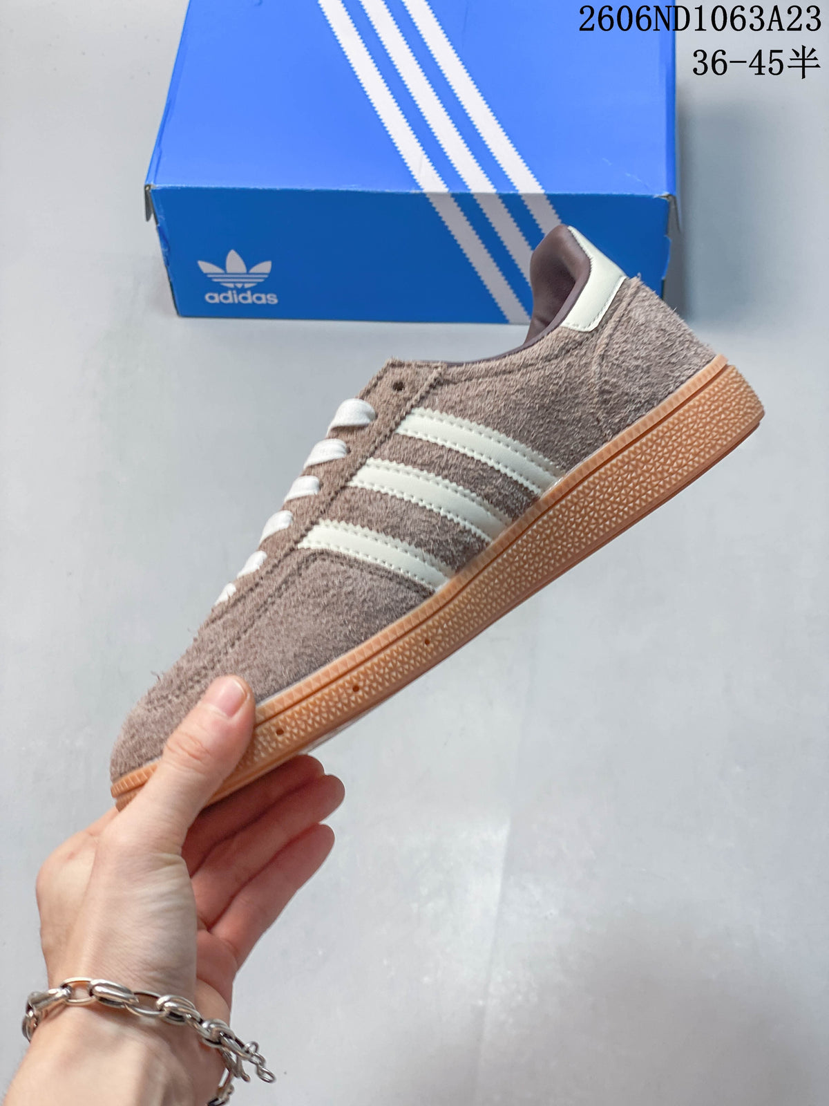 Side profile of a taupe low-top sneaker with off-white stripes and a gum-colored sole.