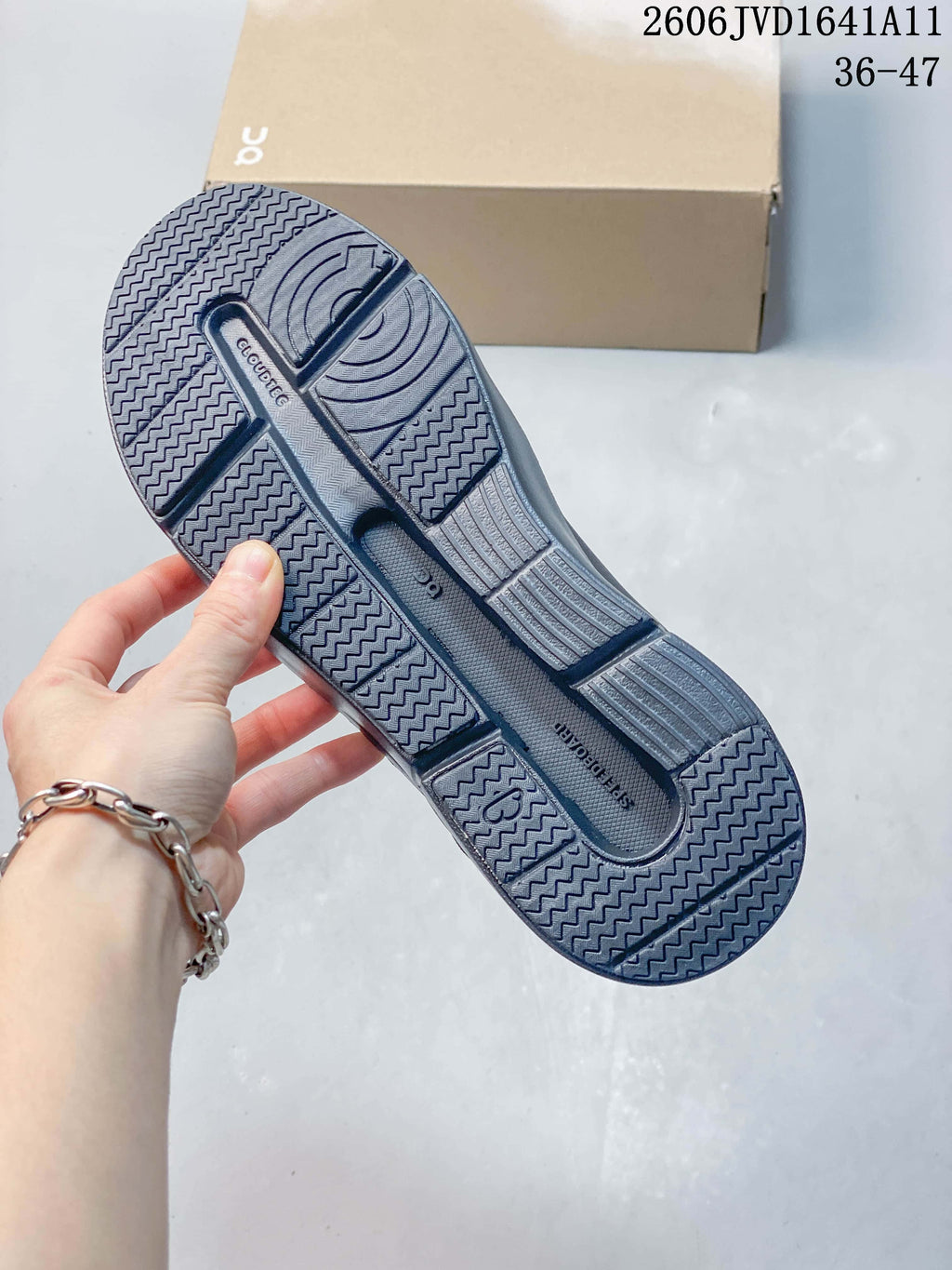 Underside of a slate-blue sneaker showing a patterned outsole