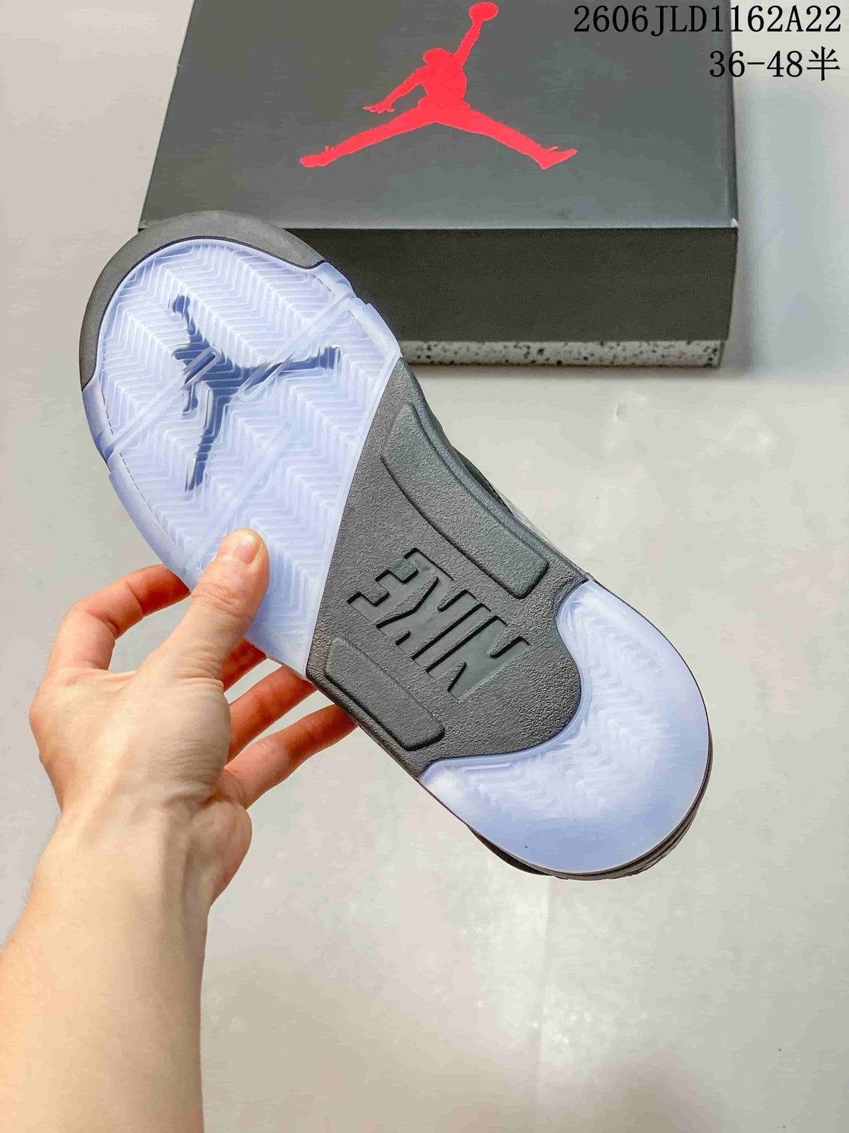 Translucent outsole of a dark high-top sneaker, with a shoe box in the background.