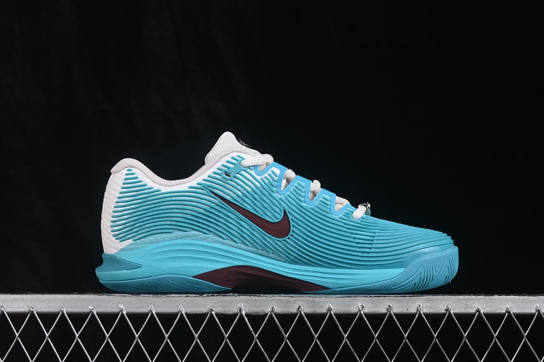 Side profile of aqua and white Nike Zoom Vapor 12 sneakers with burgundy Swoosh detail.