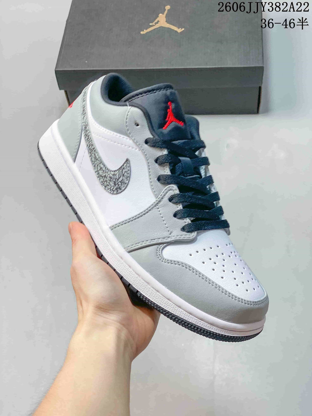 White and gray low-top sneaker with a patterned gray Swoosh, dark laces, and red tongue logo.